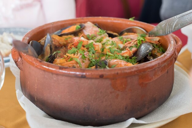 Arroz de mariscos en olla de cerámica marrón en restaurante