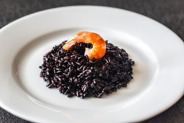 Arroz negro con camarones en plato blanco