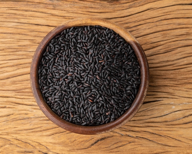 Arroz negro crudo en un bol sobre una mesa de madera