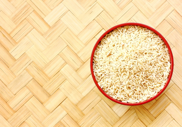 Arroz orgánico en el piso de bambú. Extraiga el arroz en un tazón o en una cuchara en el piso de bambú .topview, espacio de la copia.