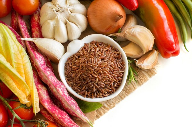 Arroz orgánico rojo en un tazón y verduras frescas de cerca