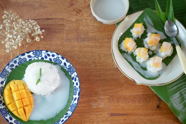 Arroz pegajoso com manga madura em sobremesas tailandesas autênticas de leite de coco em uma mesa de madeira