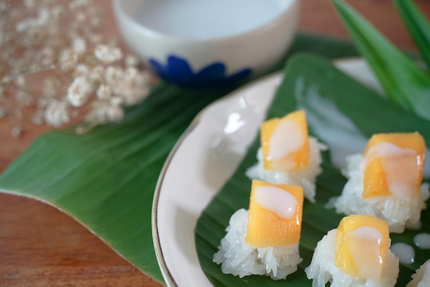 Arroz pegajoso con mango maduro en leche de coco Auténticos postres tailandeses en una mesa de madera