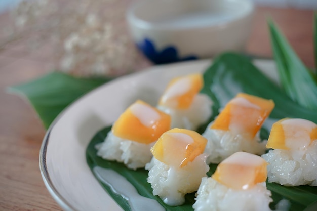 Arroz pegajoso con mango maduro en leche de coco Auténticos postres tailandeses en una mesa de madera