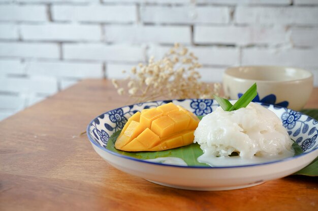 Arroz pegajoso con mango maduro en leche de coco Auténticos postres tailandeses en una mesa de madera