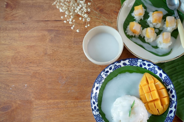 Arroz pegajoso con mango maduro en leche de coco Auténticos postres tailandeses en una mesa de madera