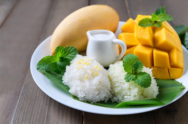 Arroz pegajoso con sabor a coco y mango maduro en un plato de madera Postres tailandeses populares en verano