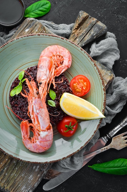 Arroz preto com camarão e legumes No fundo antigo Vista superior Espaço livre para o seu texto