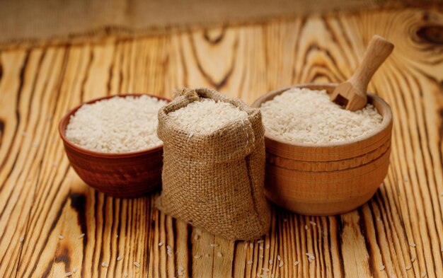 Arroz pulido largo en tazones y bolsas sobre un fondo de madera Foto de alta calidad