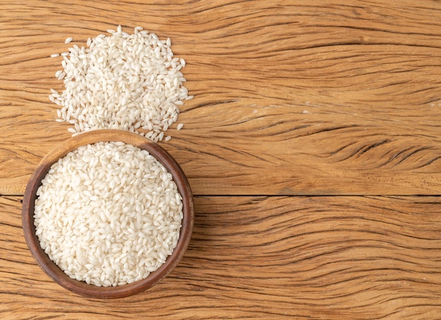 Arroz risotto carnaroli crudo en un bol sobre una mesa de madera con espacio para copiar