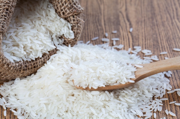 Arroz en sacos y en una cuchara de madera para poner sobre una mesa de madera