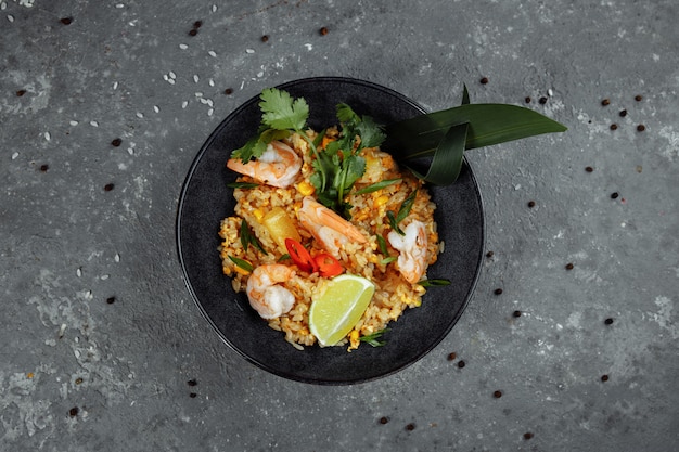 Arroz tailandês com camarão em uma placa preta em um fundo escuro. local dos direitos autorais