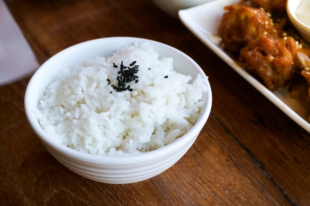 Arroz en taza blanca sobre fondo de madera y sésamo negro