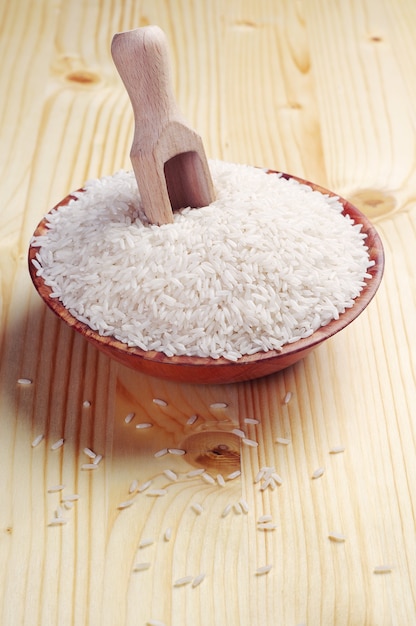 Arroz en un tazón y cuchara sobre mesa de madera