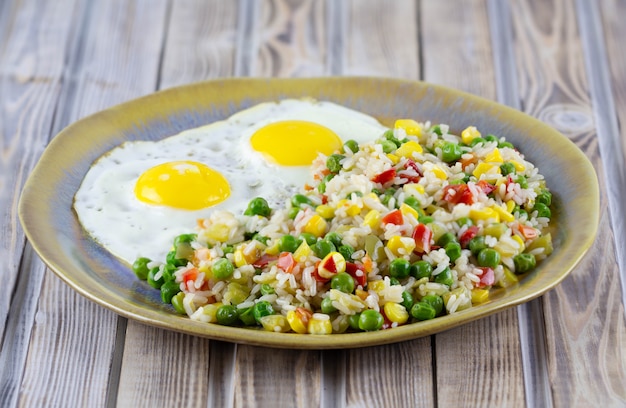 Arroz con verduras pimienta, guisantes, maíz y huevos fritos en un plato