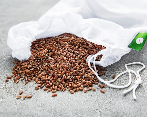 Arroz vermelho cru em uma mesa de concreto cinza