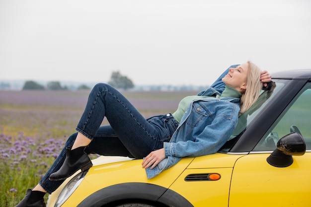 Art blonde Frau mit einem Auto nahe Blumen in der Herbstzeit abgelegt