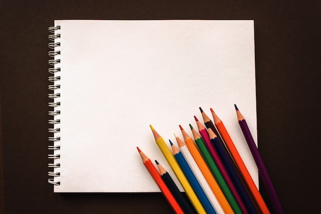 Art Sketchpad lápis de cor sobre fundo marrom, de volta ao conceito de escola. Acessórios escolares, espaço ou texto plano