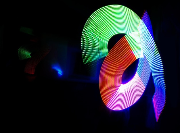 Arte abstracto e ilustración de luz sobre un fondo negro para brillo de energía o flujo de movimiento Patrón de neón creativo y colorido con maqueta para vibración de velocidad o textura con salpicaduras de color