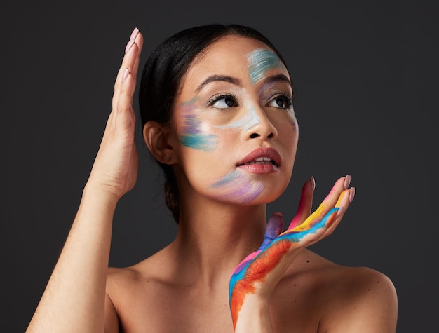 Foto arte de belleza y mujer con pintura en la cara y las manos maquillaje creativo y autoexpresión creatividad estética y cosméticos artísticos de color cuidado de la piel y libertad de expresión para una joven hermosa