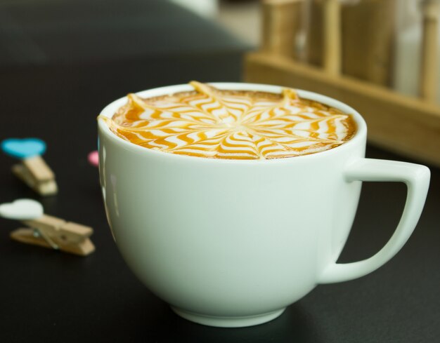 Un arte del café con leche en el escritorio negro.