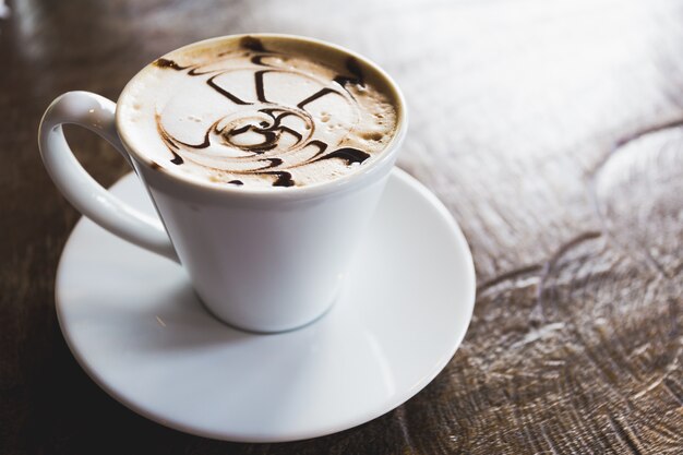 arte del café en la taza blanca en la cafetería de la cafetería de madera de la tabla