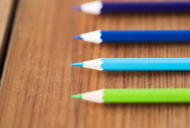 arte, color, dibujo, creatividad y concepto de objeto: cierre de crayones o lápices de colores sobre una mesa de madera