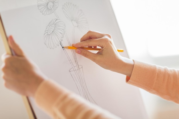 Foto arte creatividad y gente concepto artista manos con grafito lápiz dibujo de naturaleza muerta imagen de una flor en un jarrón en papel en el estudio