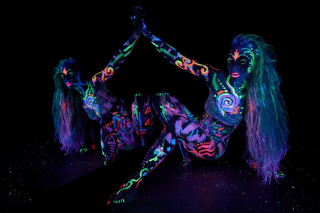 Arte de cuerpo de mujer de arte en el cuerpo bailando en luz ultravioleta