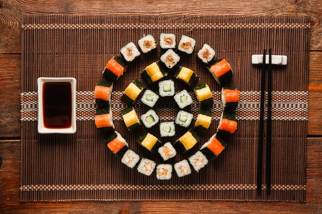 Arte culinária japonesa. Deliciosos rolos de uramaki definidos, ornamento redondo colorido de sushi servido em uma esteira de palha marrom, camada plana. Foto do menu do restaurante de luxo.
