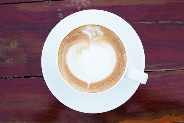 Arte de café com leite quente na xícara branca na mesa de madeira