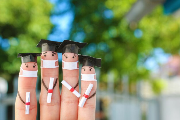 Arte de dedos de alunos em máscara médica do COVID-2019. Graduados com diploma após a formatura.