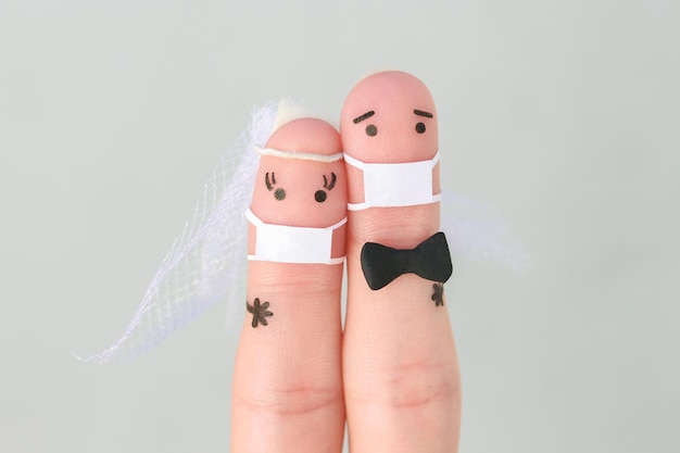 Arte de dedos de casal feliz em máscara médica do COVID-2019. Conceito de cerimônia de casamento.