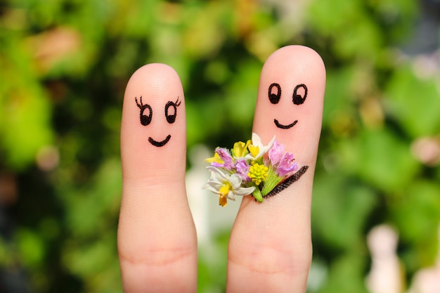 Arte del dedo de una pareja feliz. El hombre está dando flores a una mujer.