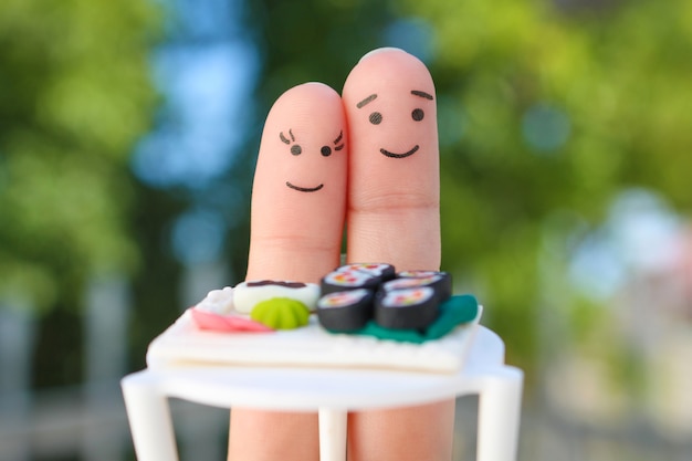 Arte de los dedos de la pareja feliz. Hombre y mujer comen sushi en la cafetería.