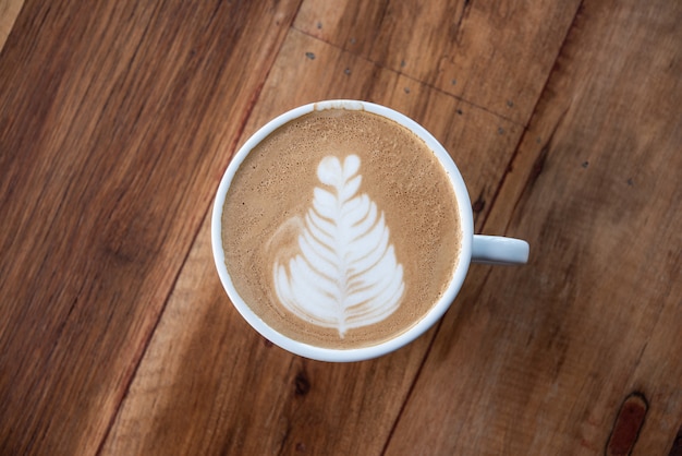 Arte do latte da xícara de café, teclado com as ferramentas do escritório no fundo cor-de-rosa. Vista superior com espaço de cópia para