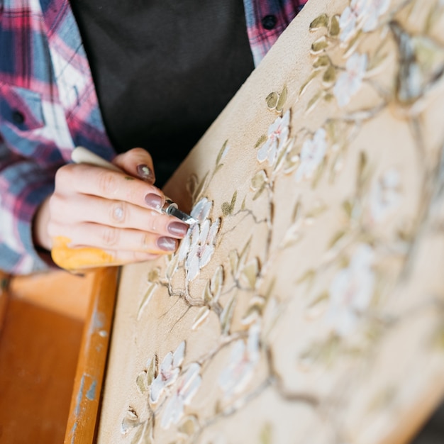 Arte de estudio. Lienzo estampado floral. Artista en el trabajo. Pintora de mujer con talla de herramienta de modelado.