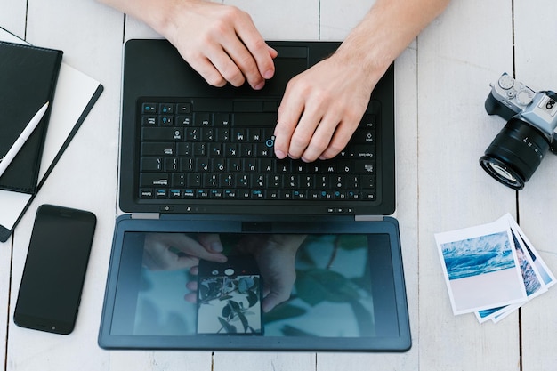 Arte fotográfica e conceito de retoque de fotos mãos de homem trabalhando na câmera de imagem de processamento de laptop e fotos impressas na mesa