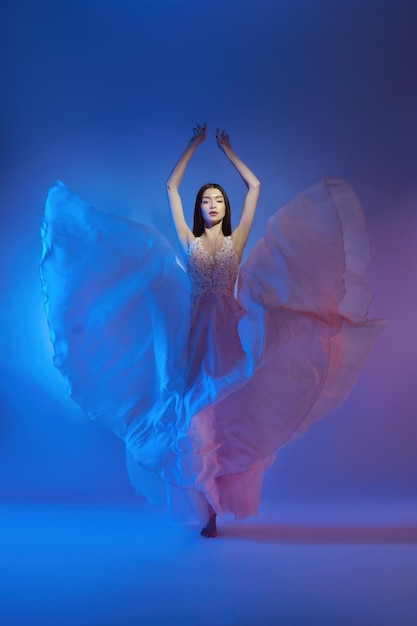 Arte hermosa mujer en vestido volador que sopla Concepto de libertad en luz de color neón Estilo de moda de vestido que fluye en el cuerpo mujer Vestido volador Revoloteando en el viento