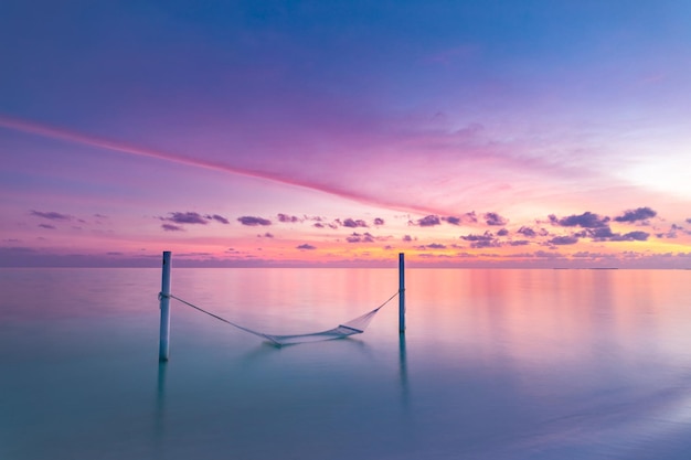 Arte hermosa puesta de sol sobre la playa tropical, columpio o hamaca sobre el mar en calma, colorido cielo de ocio