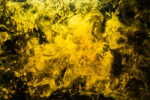 Arte líquido abstracto, bomba de humo amarillo sobre fondo negro, pinturas acrílicas de color ámbar bajo el agua