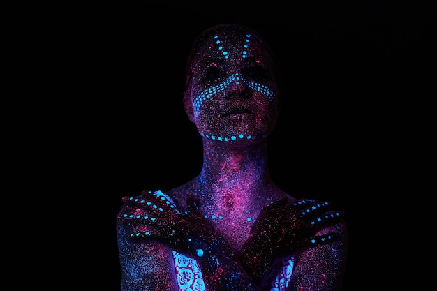 Arte mujer cosmos en luz ultravioleta. Todo el cuerpo está cubierto de gotitas de colores.
