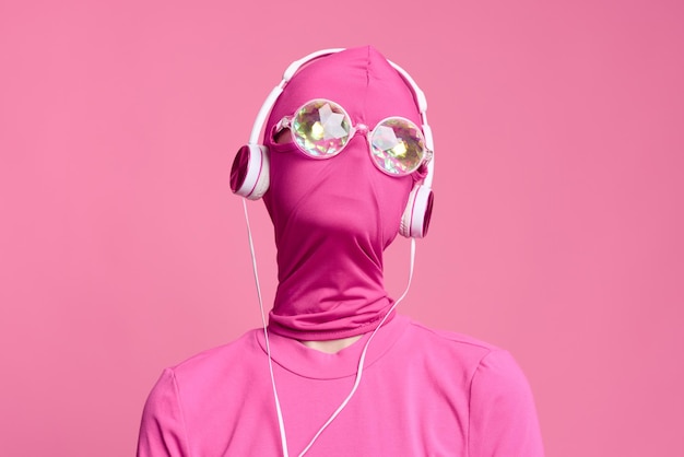 El arte de la mujer supera al retrato conceptual en cera rosa brillante con gafas de neón brillantes, máscara rosa y auriculares