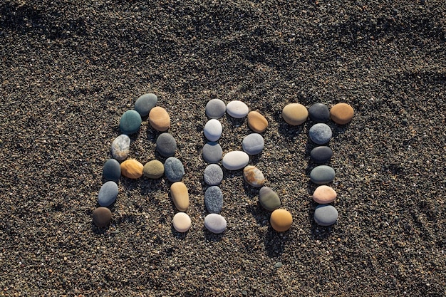 Arte de la palabra hecho de piedras en la playa de arena