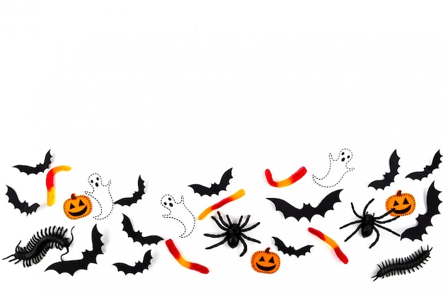 Arte de papel de Halloween. Volando murciélagos de papel negro, escarabajos y arañas, caramelos, calabazas y fantasmas en blanco.