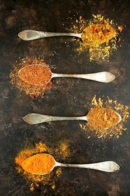 Arten von verschiedenen Gewürzen in Löffeln auf einem dunklen Tisch Kochen von Speisen Flachlage