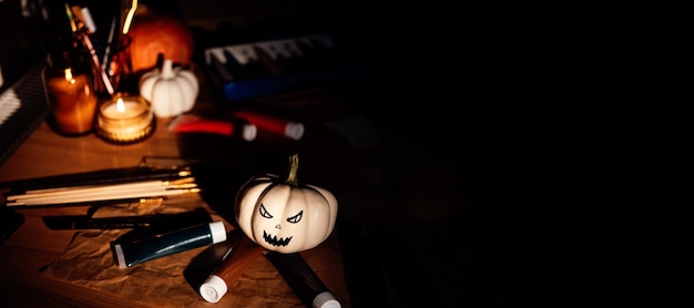 Artes e ofícios de Halloween pintando escovas de abóboras e tintas sobre a mesa na noite escura