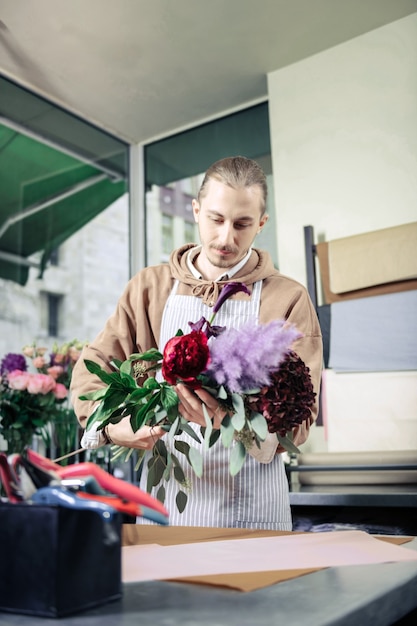 Artes favoritas. Homem bonito expressando positividade enquanto olha para as plantas