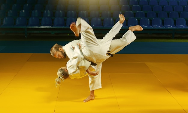 Artes marciales. Portadores ahorradores. Deporte hombre y mujer en kimono blanco tren judo lanza y captura en el pabellón de deportes