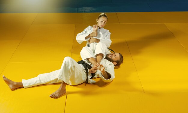 Foto artes marciales. portadores ahorradores. deporte hombre y mujer en kimono blanco tren judo lanza y captura en el pabellón de deportes